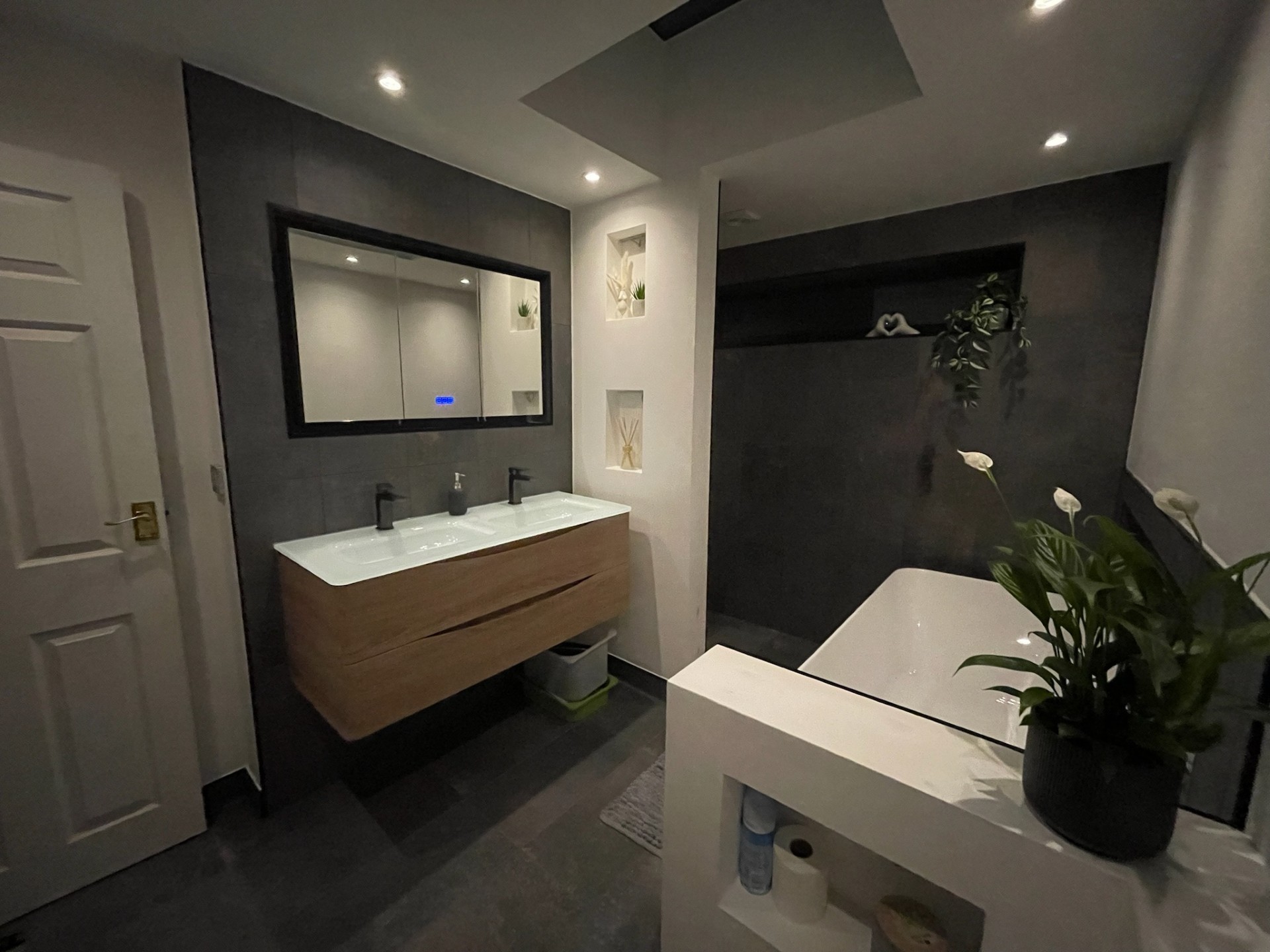 Double floating vanity with freestanding bath and dark tiles