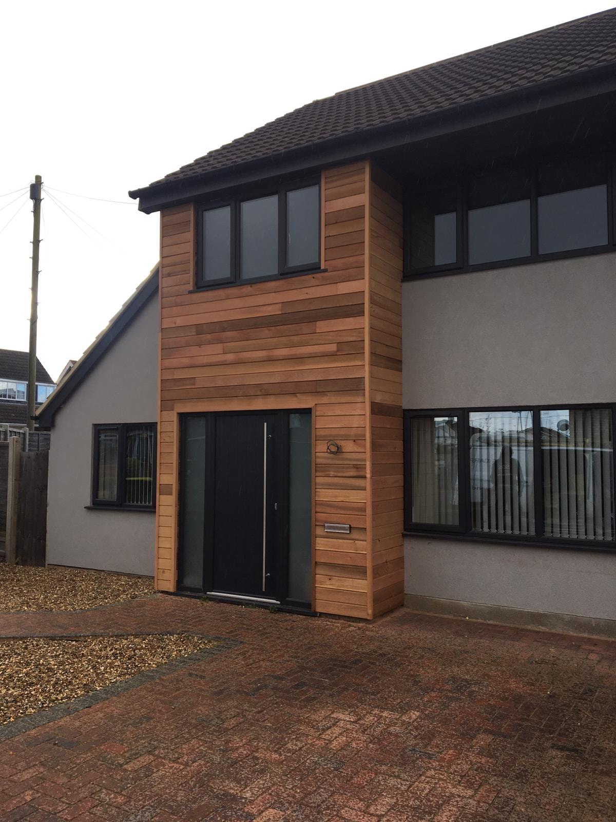 Cedar cladding completed on house exterior with black door and windows