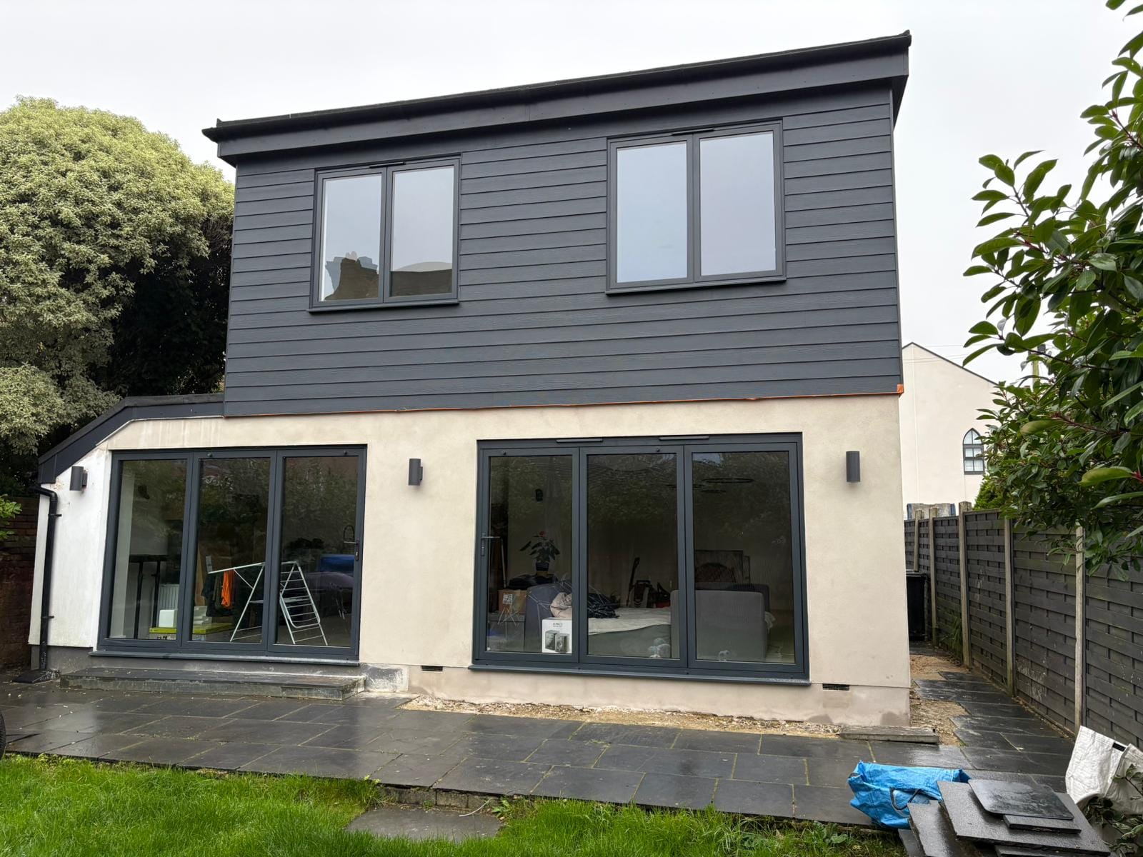 Two-storey extension with dark cladding and bifold doors